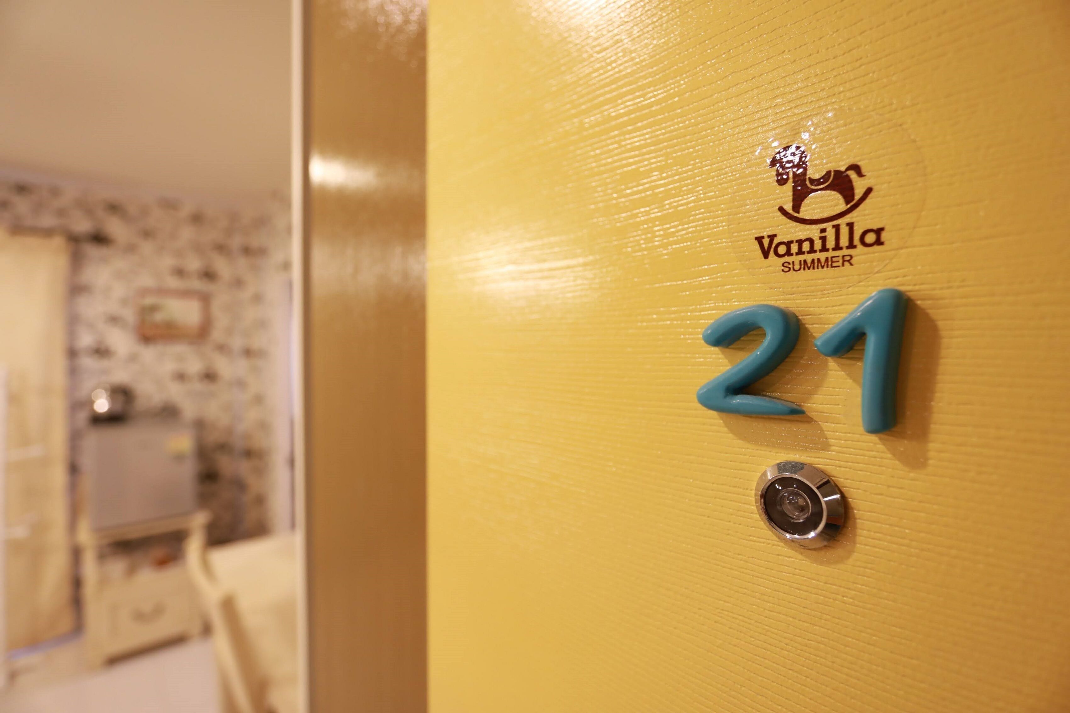 A yellow door with the number 21 and the logo "Vanilla Summer" on it.