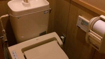 Et lille, kompakt badeværelse med toilet, bidet og en papirhåndklædedispenser.