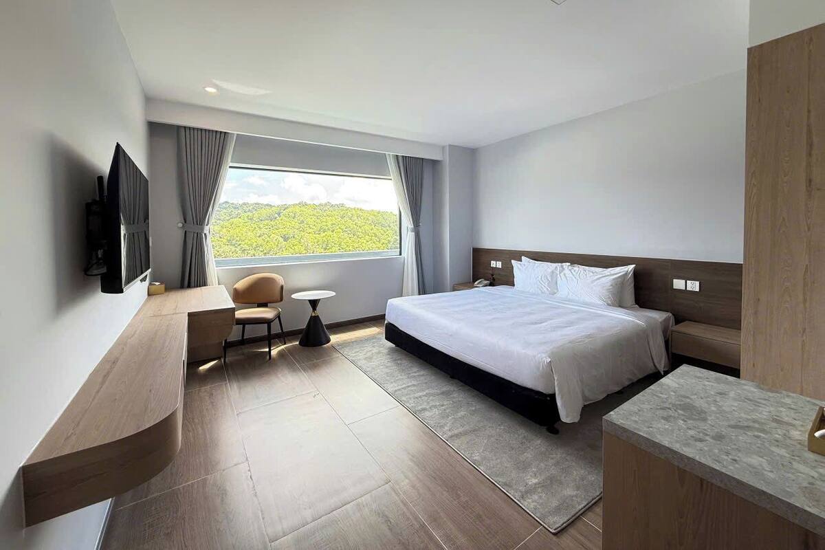 Une chambre d’hôtel moderne, dotée d’un grand lit, d’un bureau, d’une chaise et offrant une vue sur l’extérieur.