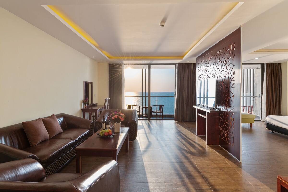 Une chambre d’hôtel moderne avec un canapé en cuir, une table à manger et une vue sur l’océan.