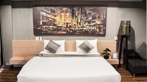 Een moderne slaapkamer met een groot bed, een hoofdeinde met ingebouwde opbergruimte, een nachtkastje, een vloerlamp en een stadslandschap schilderij aan de muur.