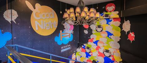 Una escalera con barandas de colores y una pared decorada con un cartel que dice 'Good Night' y un mural de ovejas.