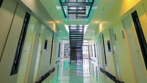 Een moderne hotelgang met een hoge plafond, glanzende vloer en meerdere deuren aan weerszijden.