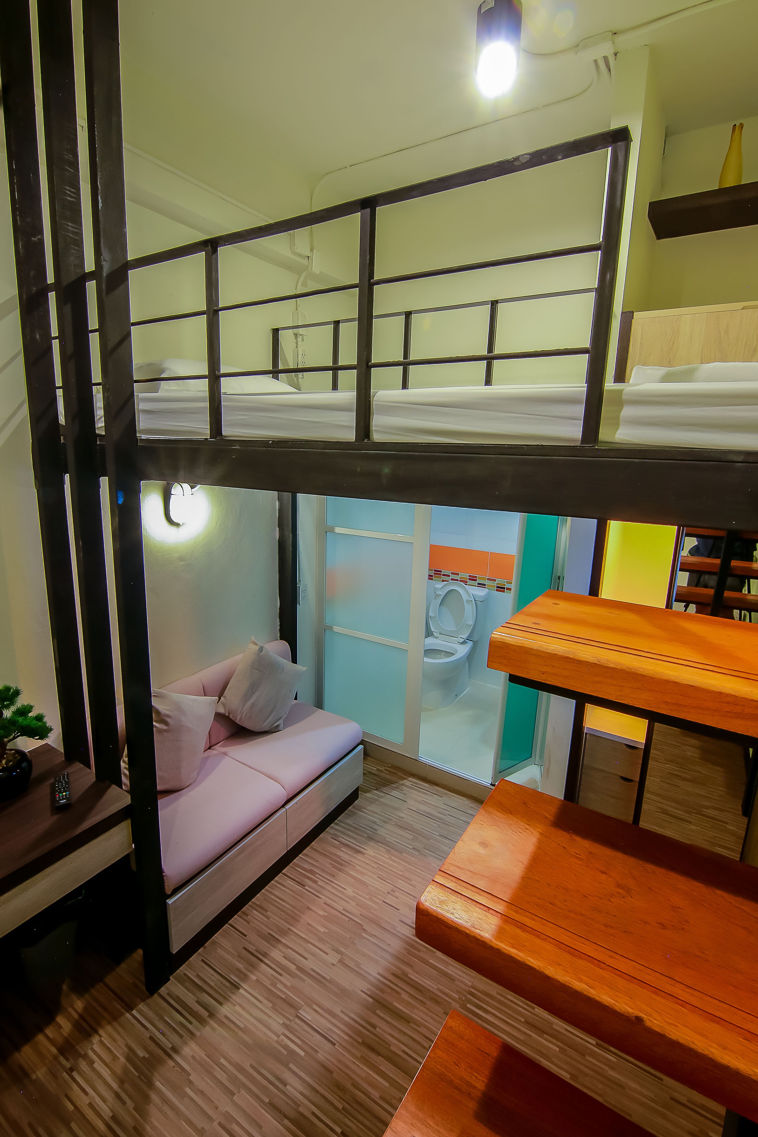 A bunk bed room with a desk and a small seating area.