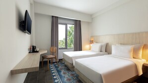 Habitación de hotel con dos camas, un escritorio, una silla, un televisor y una ventana con cortinas.