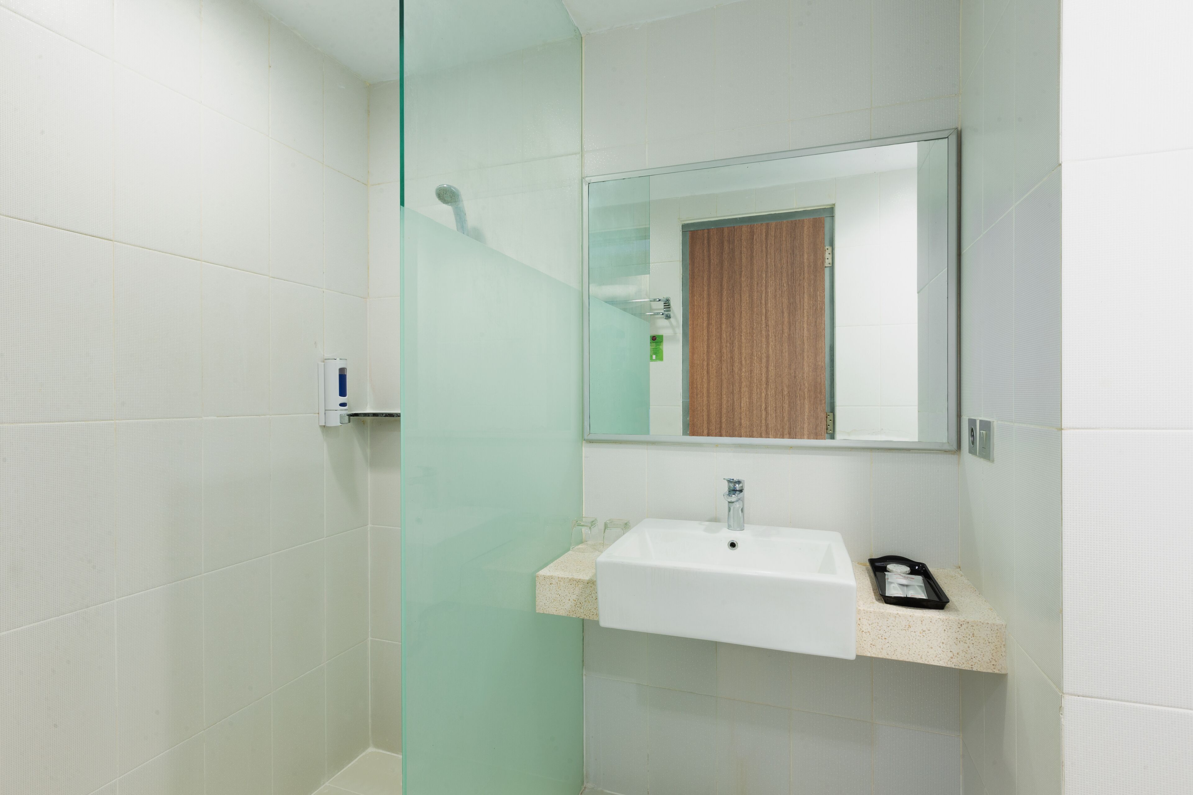 Ein modernes Badezimmer mit Duschkabine aus Glas, einem weißen Waschbecken mit Holzunterschrank und einem Spiegel darüber.