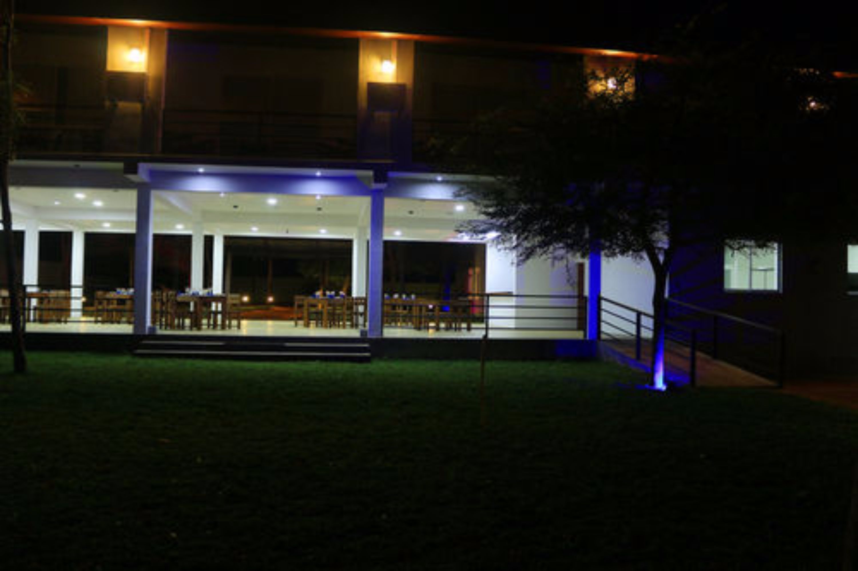 A modern building with a covered outdoor seating area and a staircase leading to the entrance.