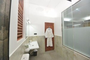 Egy fürdőszoba, amelyben WC, mosdókagyló és üvegfalas zuhanyzó található.