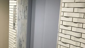 An elevator with a marble wall on one side and a brick wall on the other. - Best Hotel (Tokyo)