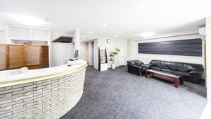 A reception area with a curved reception desk, a black leather sofa, a coffee table, and a large abstract painting on the wall. - Best Hotel (Tokyo)