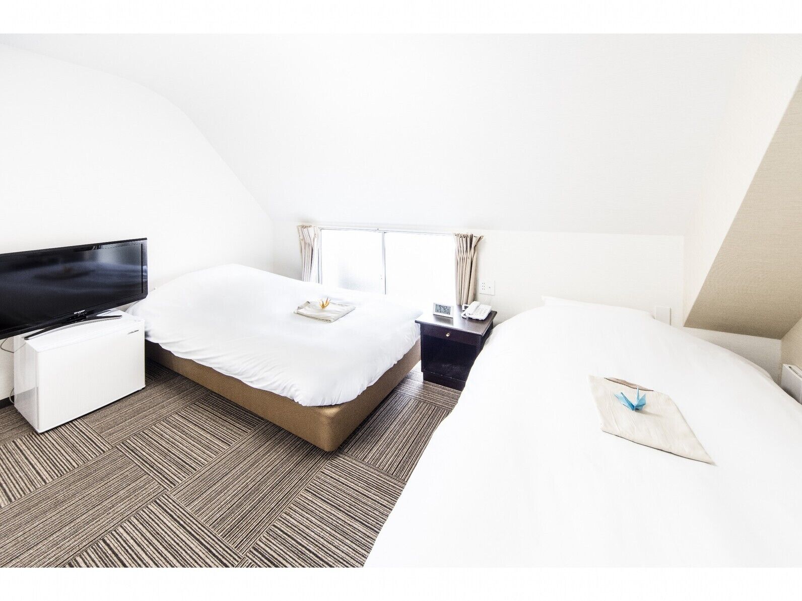 Une chambre d’hôtel équipée d’une télévision, de deux lits, d’un bureau et d’une fenêtre.