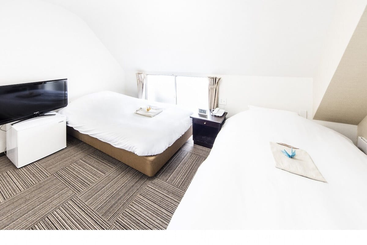 Une chambre d’hôtel équipée d’une télévision, de deux lits, d’un bureau et d’une fenêtre.