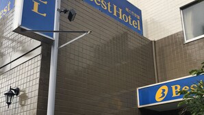 A hotel facade with a prominent 'Best Hotel' sign, a tiled exterior, and a traditional entrance with a small garden display. - Best Hotel (Tokyo)