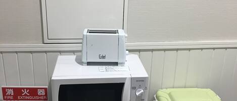 A microwave on a small table with a fire extinguisher nearby.