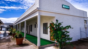 Un edificio con un toldo verde, un letrero que dice "Simon’s Place" y plantas en macetas.