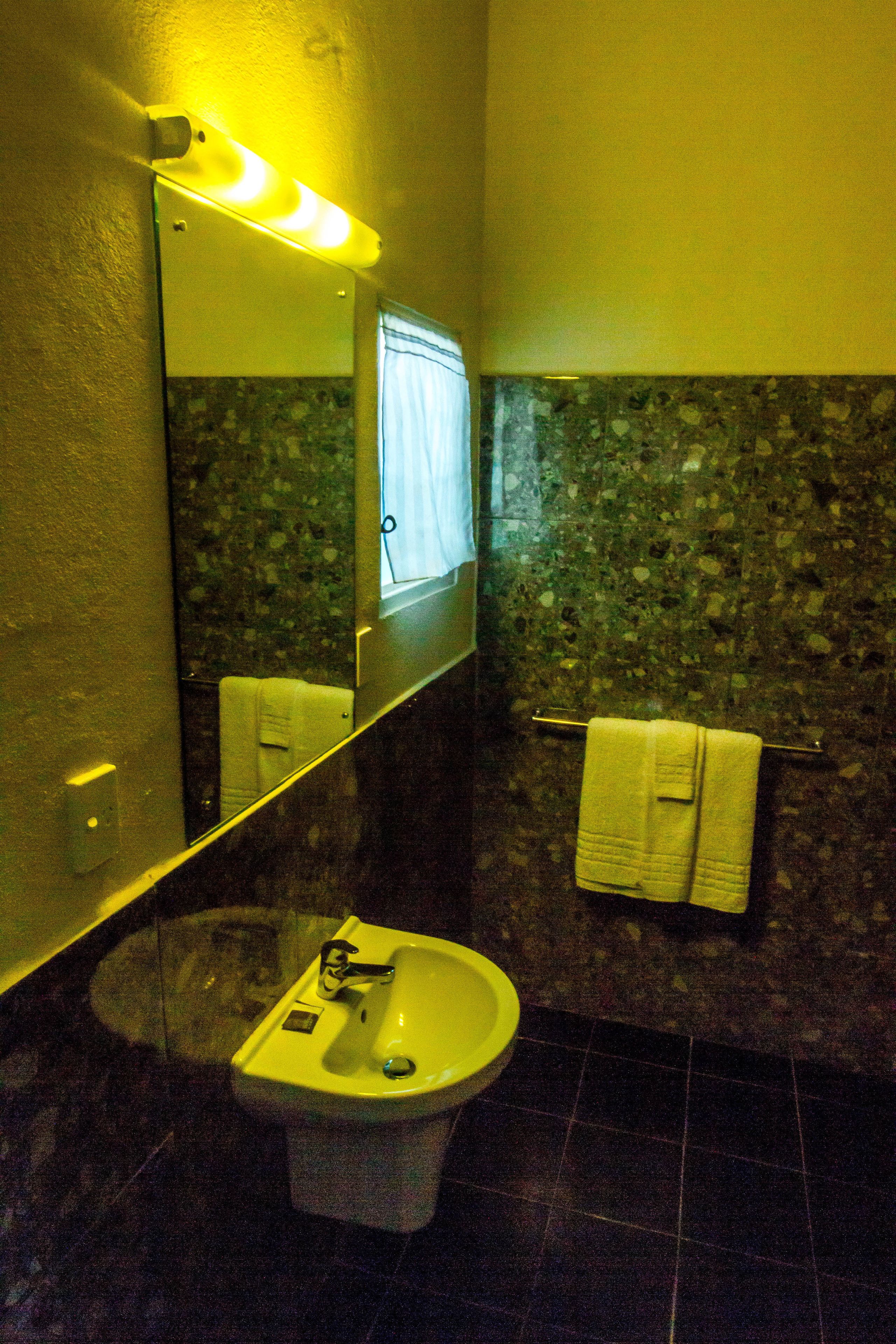 Un baño con lavamanos, espejo y toallero.