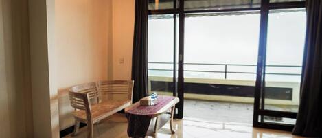 A room with a bench, a small table with a tablecloth, and a view through a large glass door.