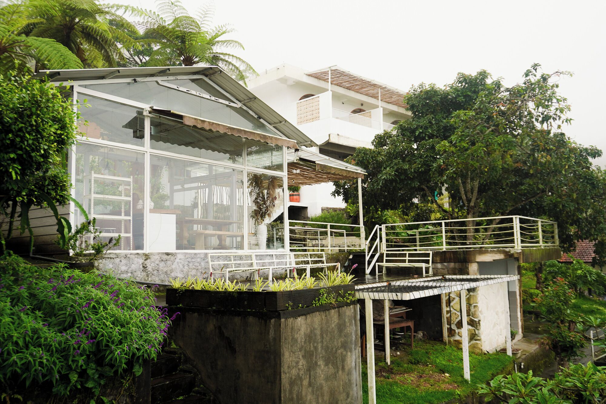 A house with a glass conservatory, a wooden deck, and a stone staircase.