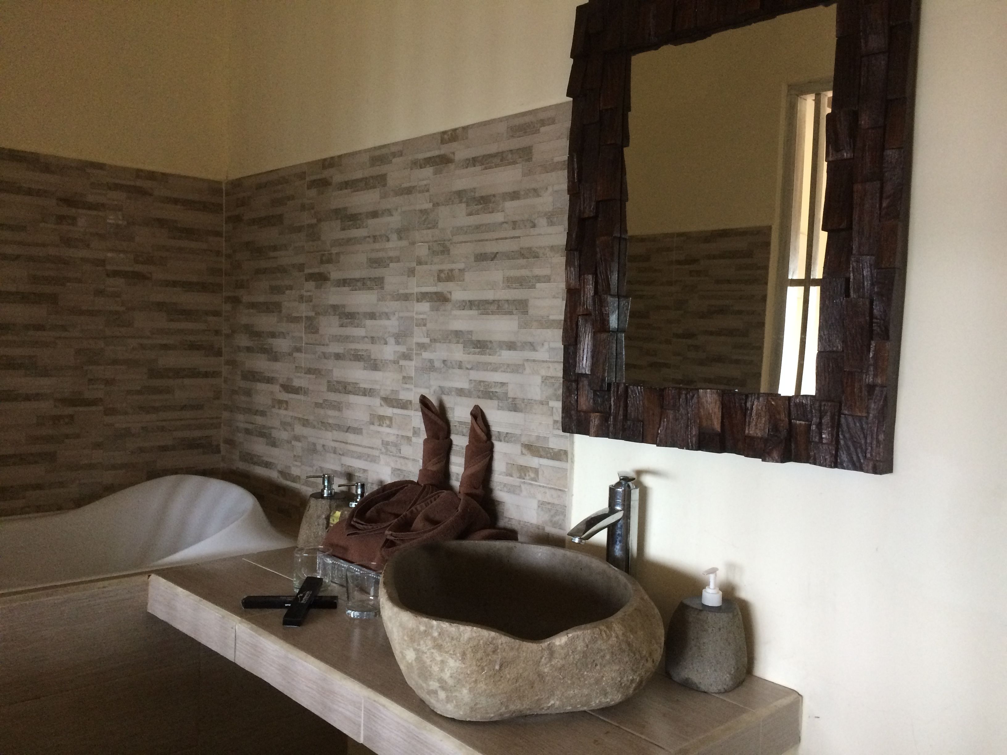 A bathroom with a stone sink, a mirror, and a bathtub.