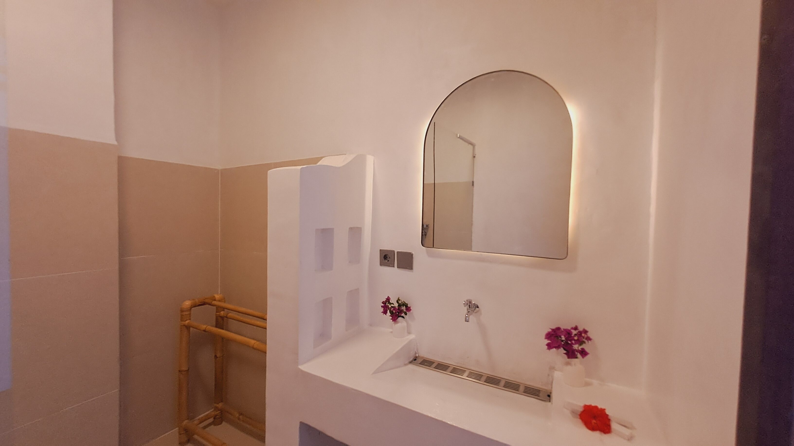 Un baño con lavamanos blanco, un espejo y zona de ducha.