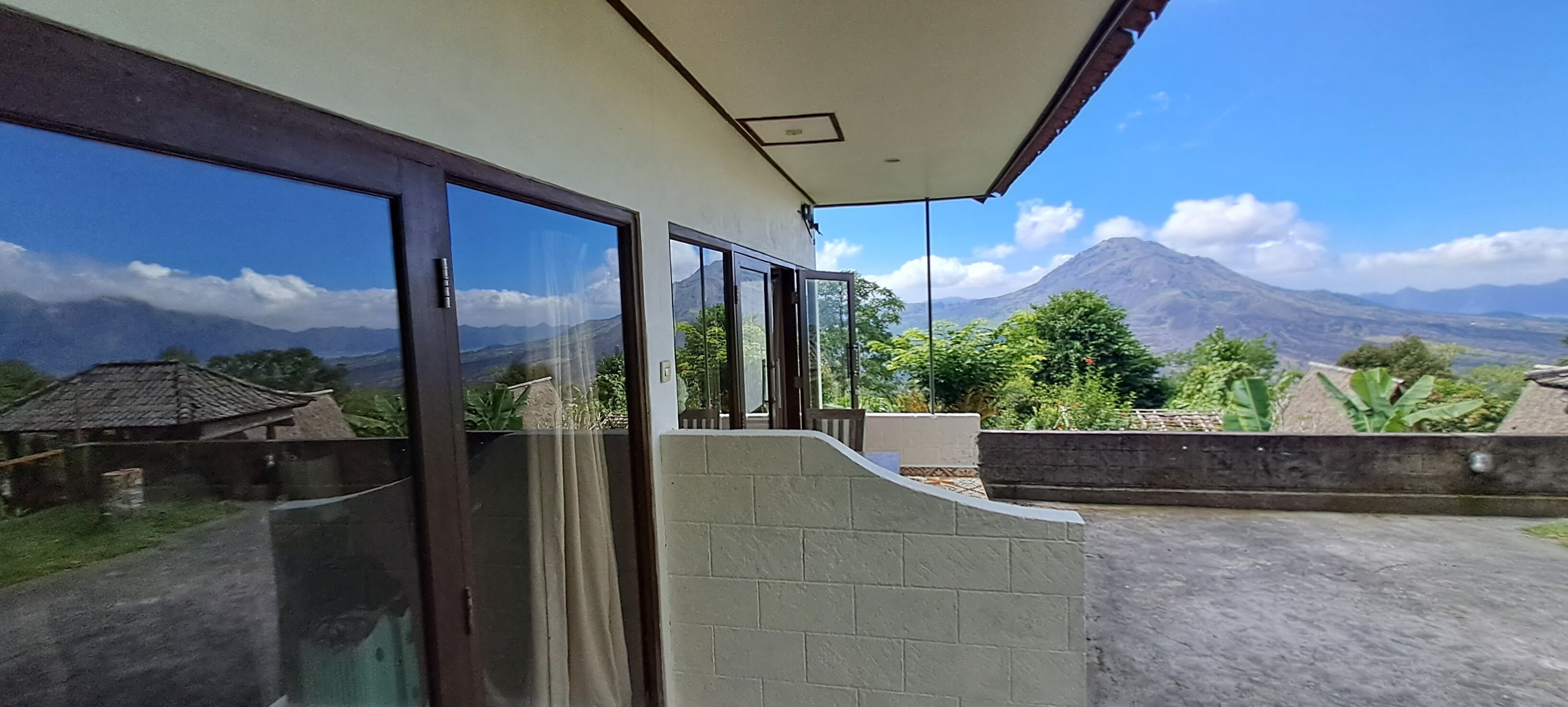 A balcony with large windows overlooking a mountainous landscape.