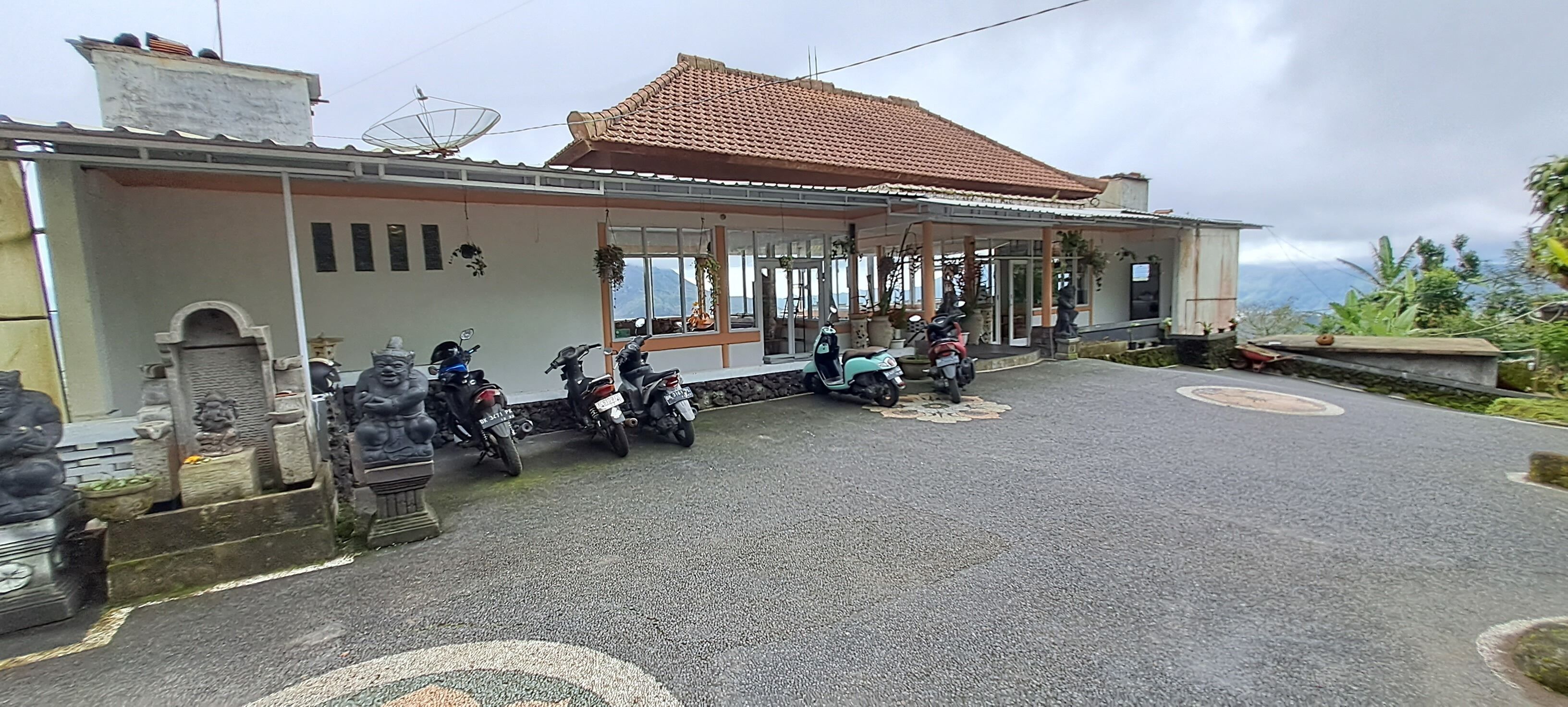 Un edificio con techo de tejas y un porche cubierto donde se ven motocicletas estacionadas.
