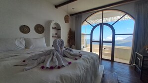 A bedroom with a large bed, a view through a glass door, and a ceiling fan.