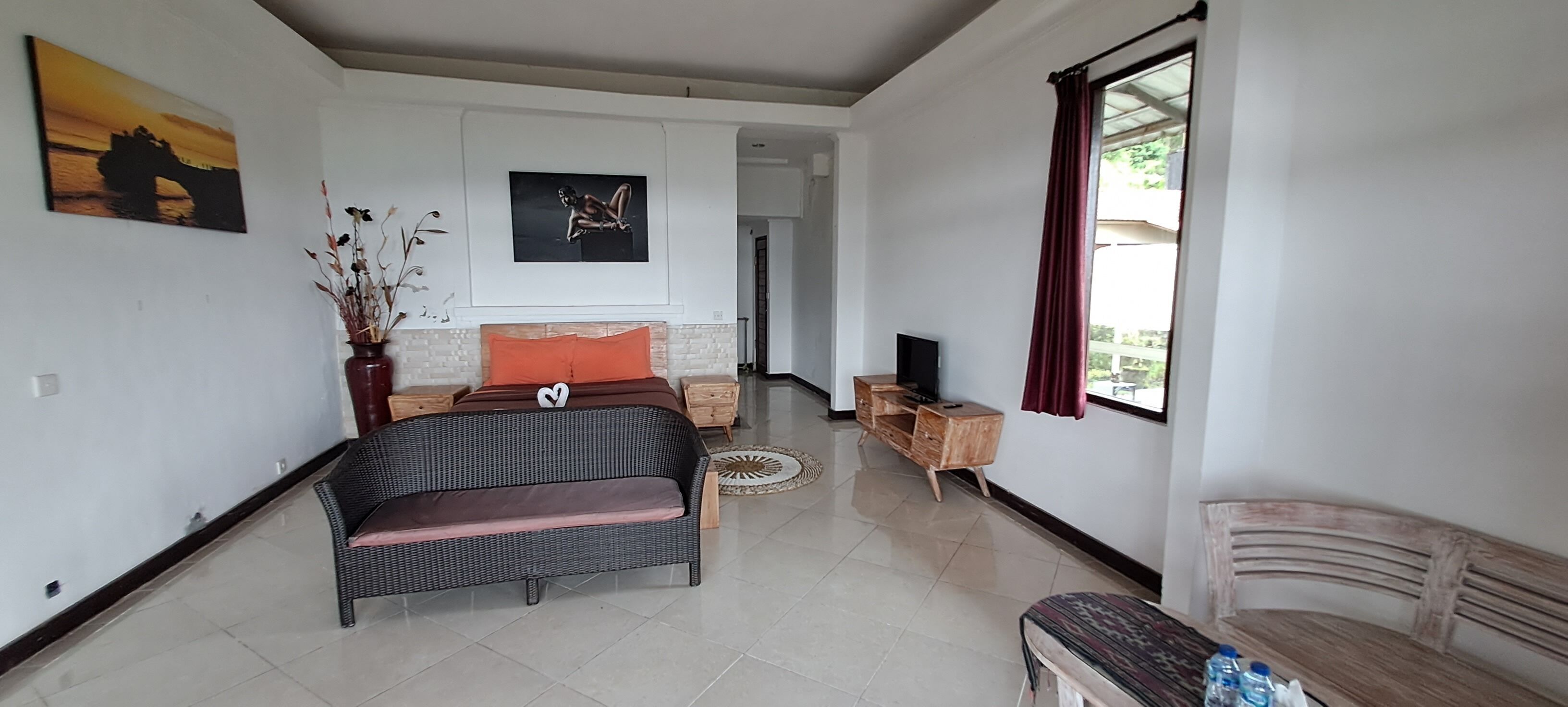 A spacious living area with a sofa, a wooden bench, a TV stand, and artwork on the walls.
