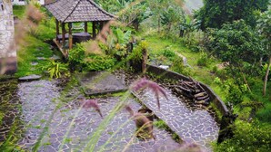 A garden with a gazebo, stone pathways, and lush greenery.