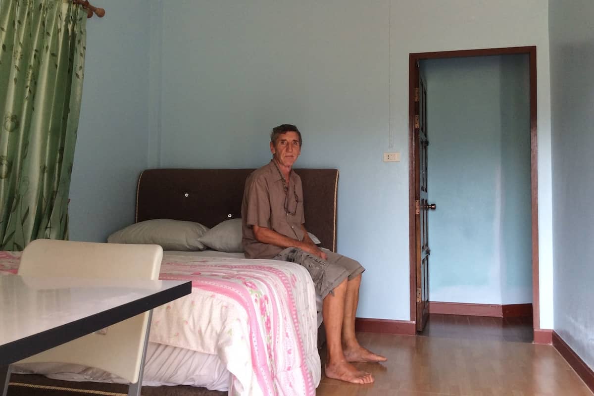 A room with a bed, a chair, and a door.