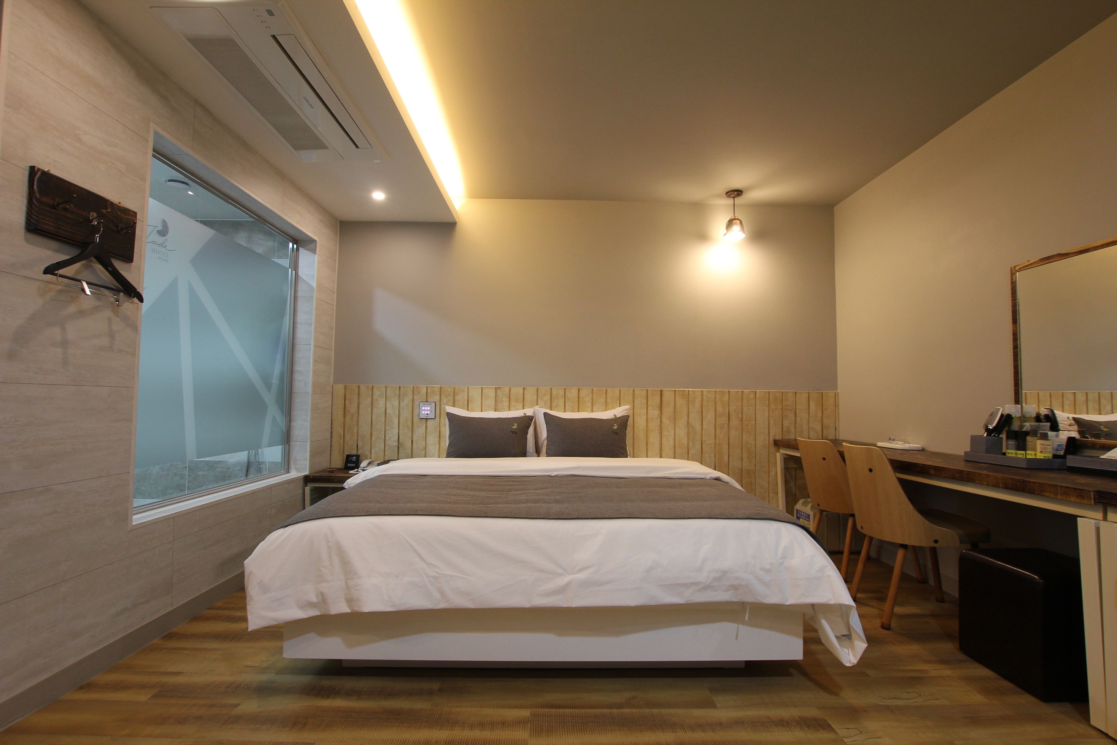 Moderni hotellihuone, jossa on suuri sänky, työpöytä ja tuoli.