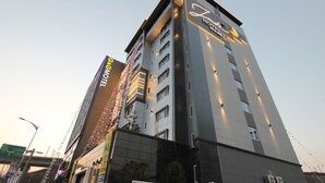 A modern hotel building with multiple floors, large windows, and a prominent sign on the top. - Jade Hotel Ulsan (Ulsan)