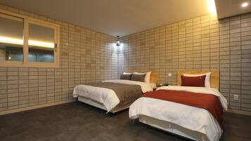 Habitación de hotel con dos camas, un espejo grande y un muro con azulejos.