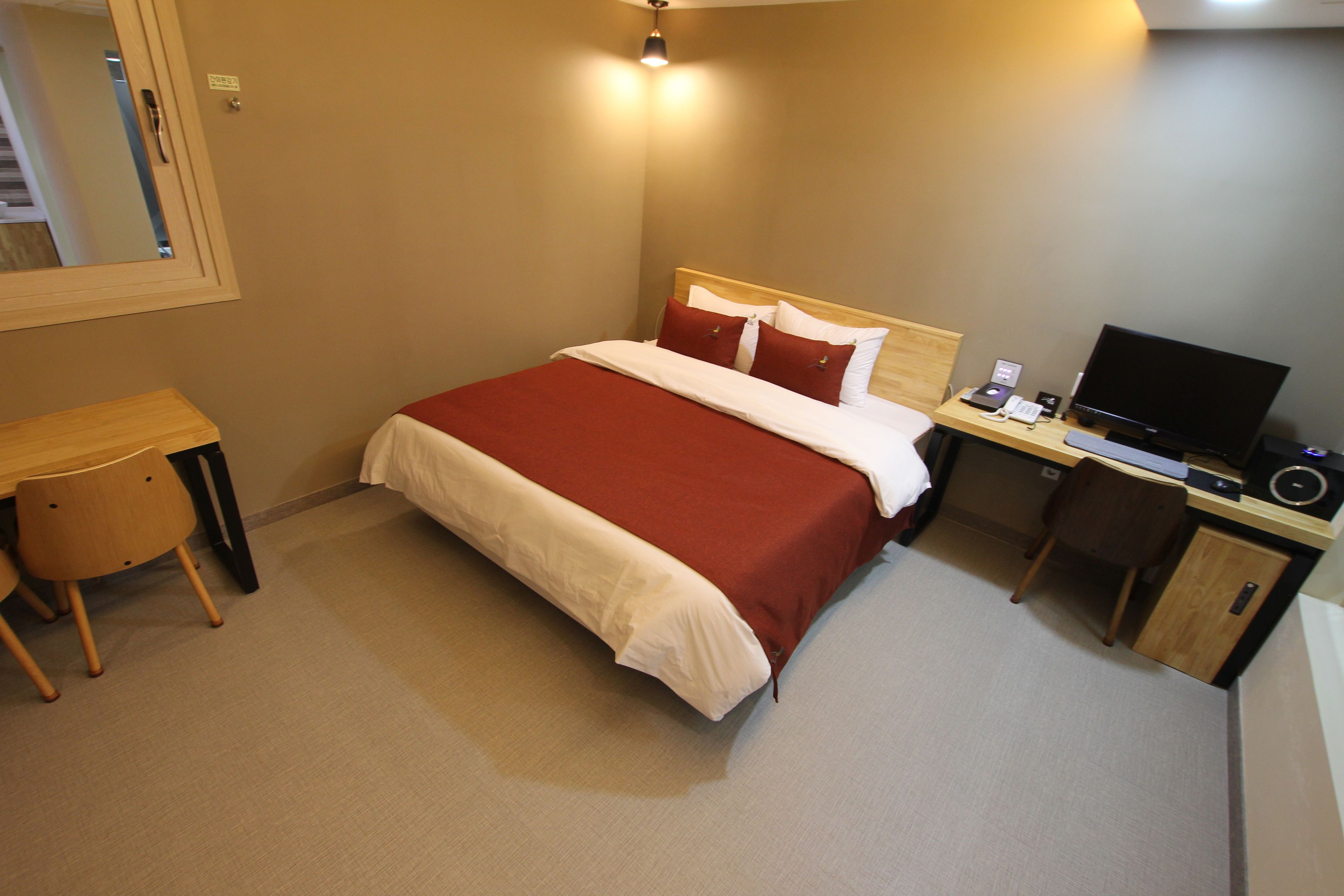 Ein Hotelzimmer mit Bett, Schreibtisch, Stuhl, Fernseher und Telefon.
