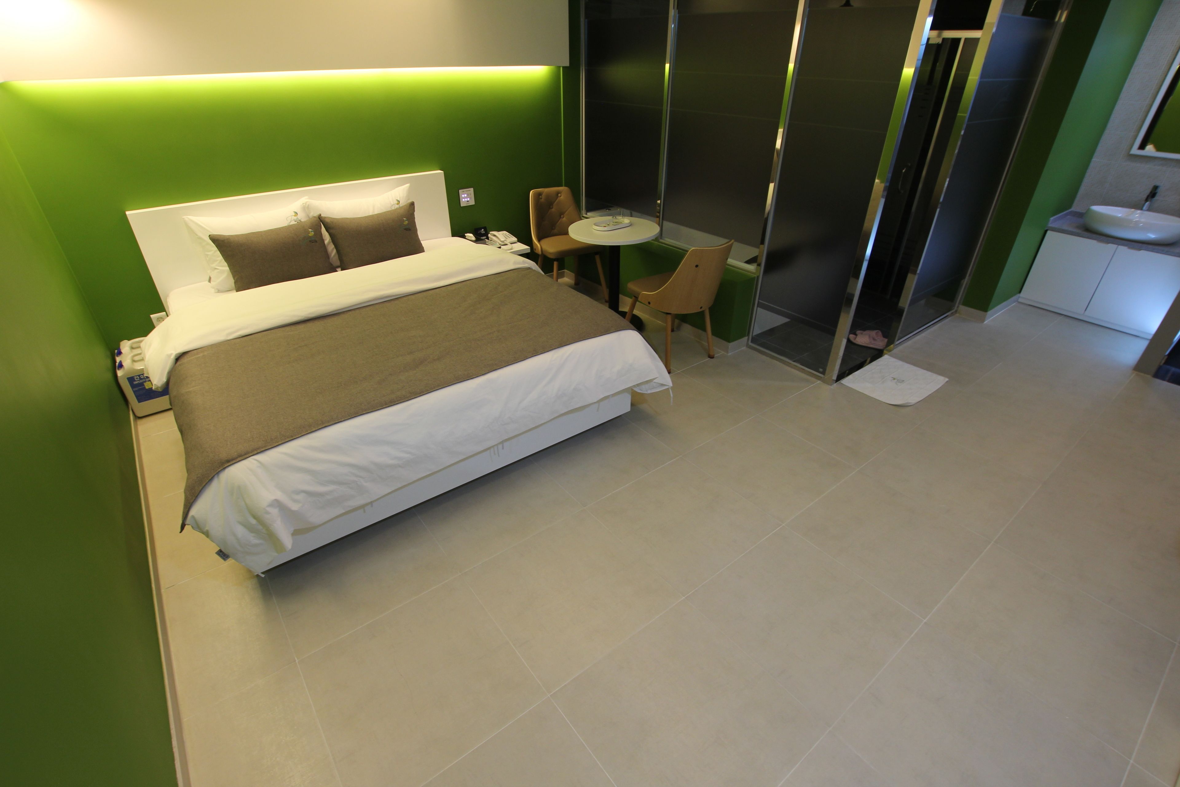 A hotel room with a bed, a small table, a chair, a bathroom, and a sink.