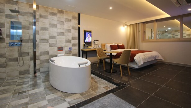 A modern hotel room with a bathtub, a dining area, and a TV. - Jade Hotel Ulsan (Ulsan)