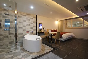 A modern hotel room with a bathtub, a dining area, and a TV. - Jade Hotel Ulsan (Ulsan)