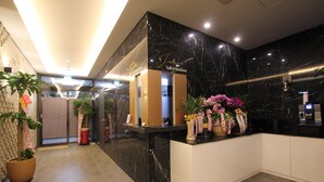 A hotel reception area with a marble counter, potted plants, and a reception desk. - Jade Hotel Ulsan (Ulsan)