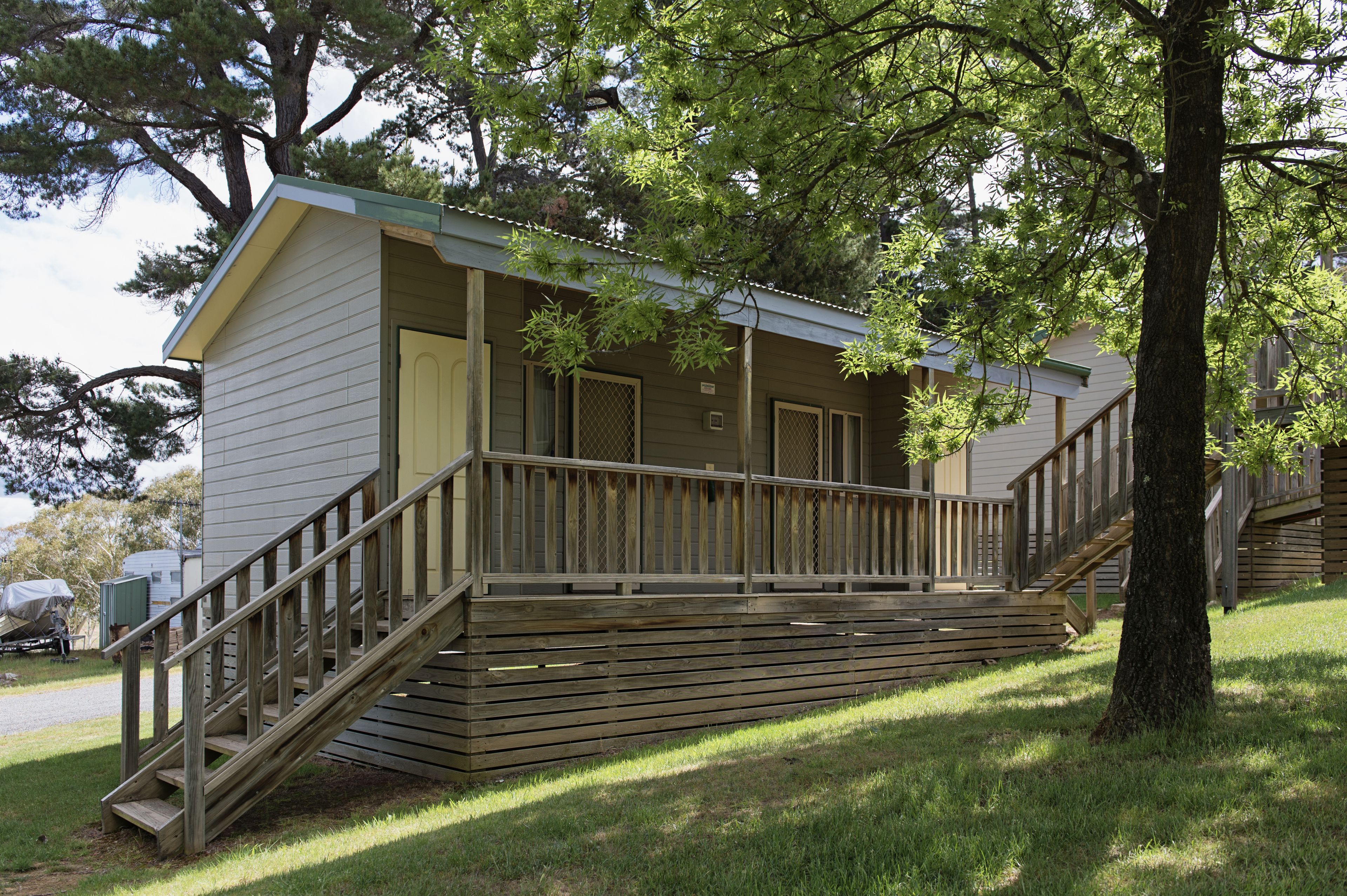 A small, single-story cabin with a wooden deck and stairs leading to a door.