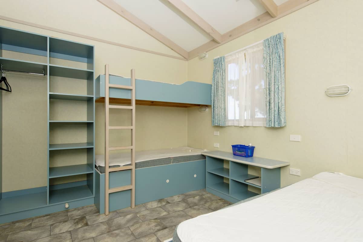 Ein Zimmer mit einem Etagenbett, einem Schreibtisch, einem Stuhl und einem Kleiderschrank.