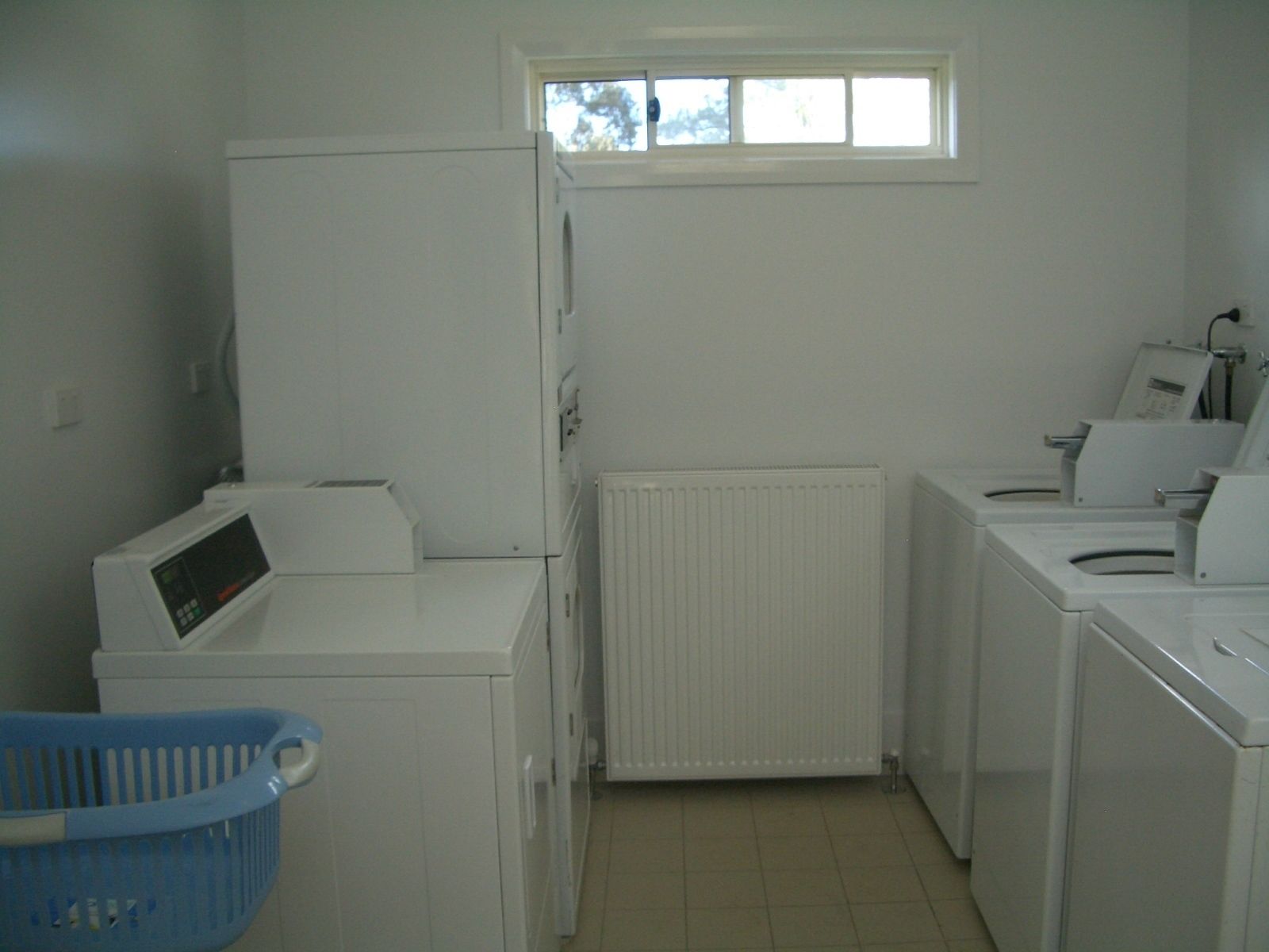 A laundry room with a washing machine, dryer, and a small window.