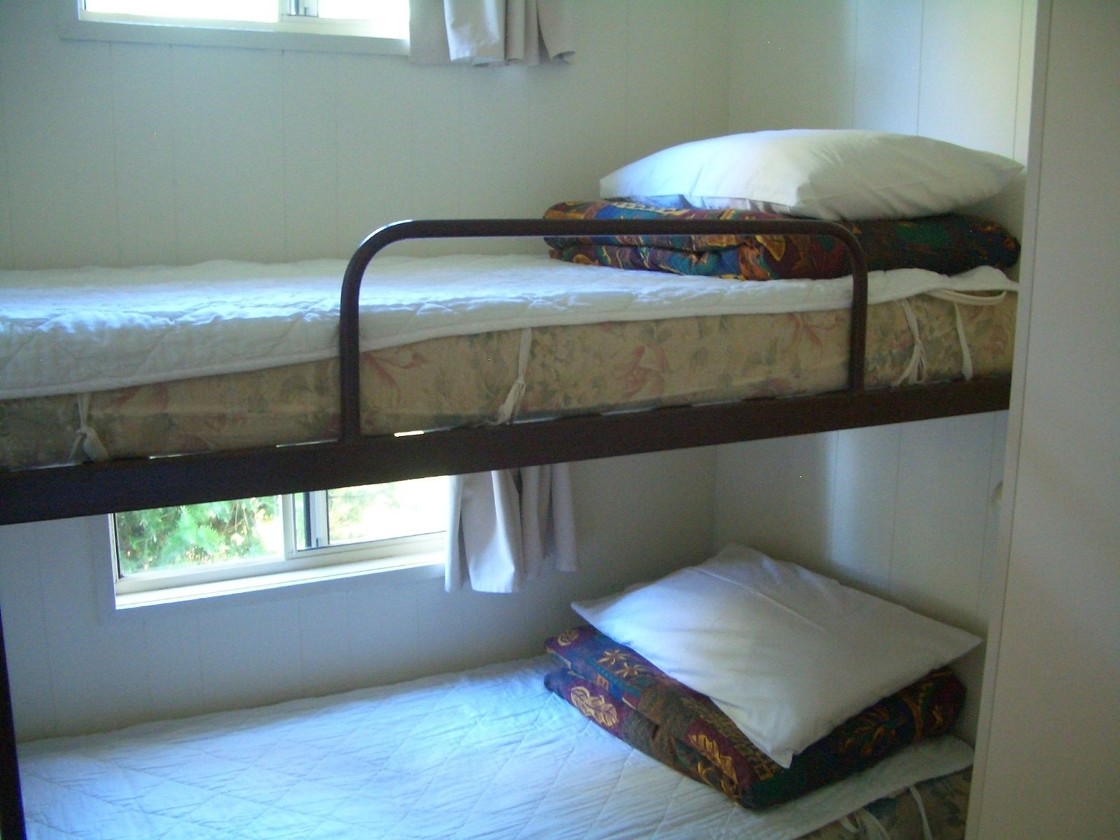 A bunk bed with two levels, each with a pillow and a blanket.