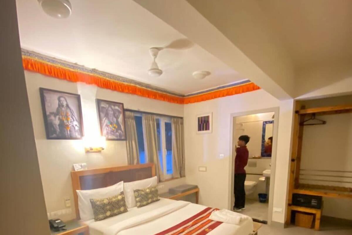 A hotel room with a large bed, a bedside table, a nightstand, and a wardrobe.