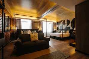 A modern hotel room with a sofa, a bed, and a large mirror.
