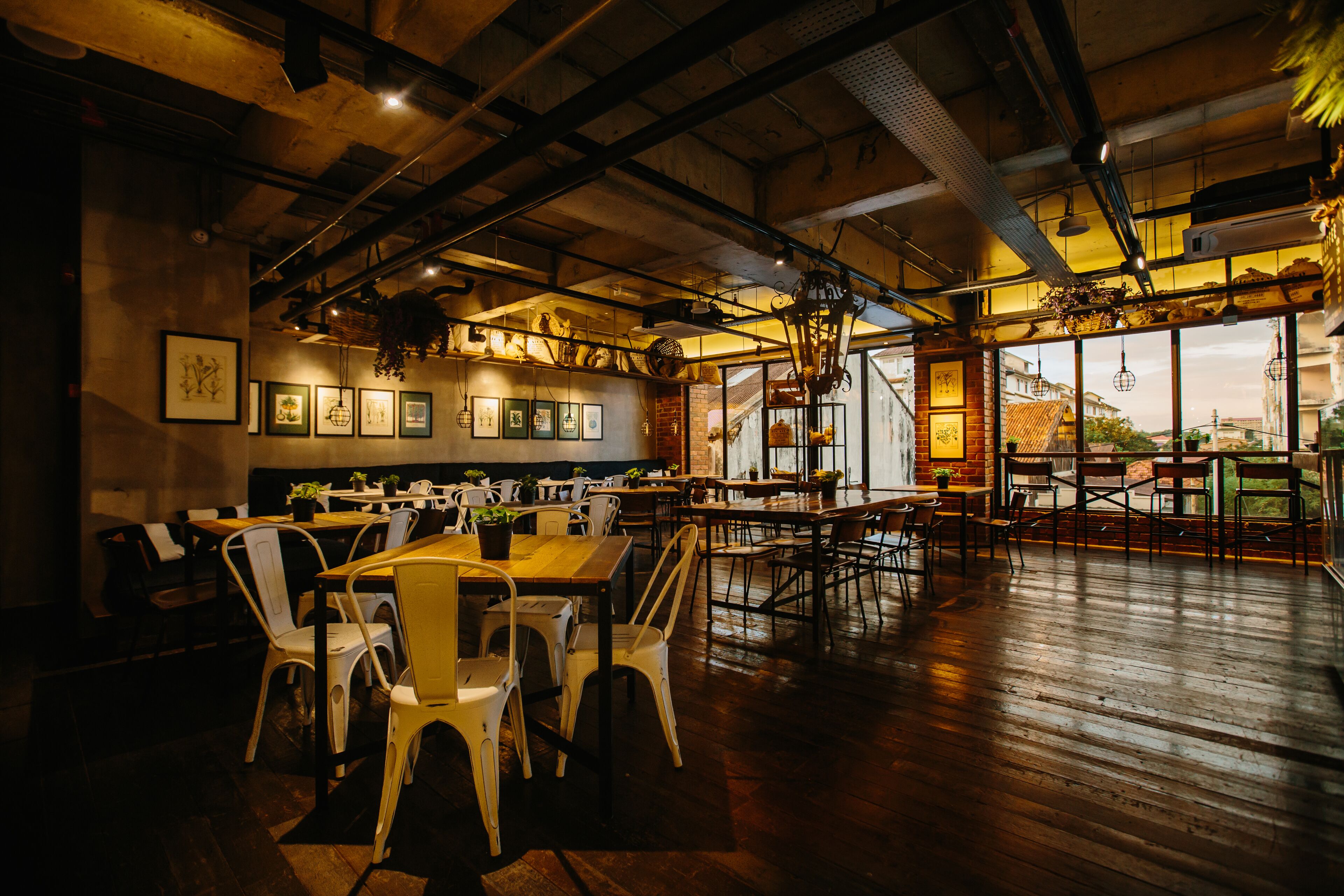 A spacious restaurant with high ceilings, exposed beams, and a mix of wooden and metal furniture.