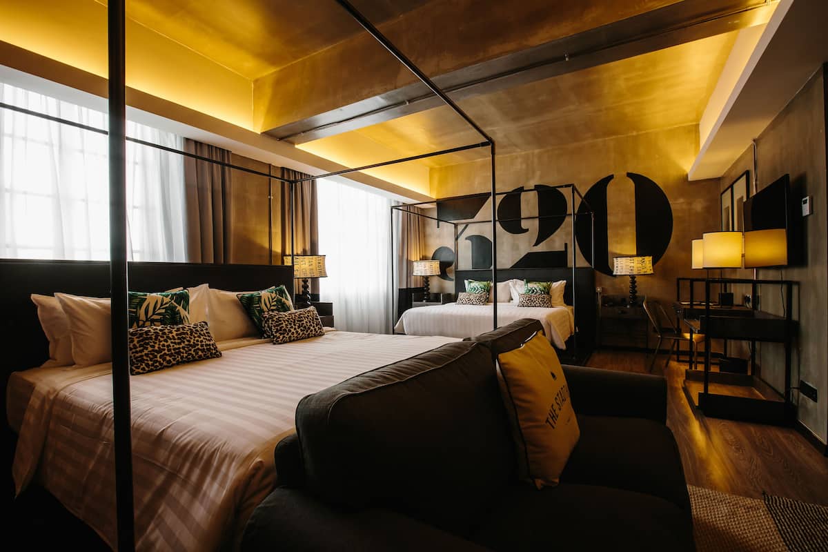 Ett modernt hotellrum med två sängar, ett skrivbord och ett stort fönster.