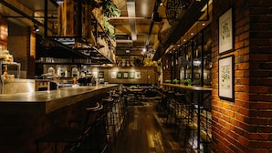 A restaurant with brick walls, wooden floors, and multiple tables and chairs. - Rosa Malacca (Malacca City)