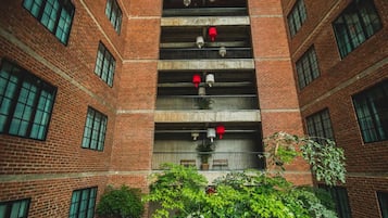 A multi-story brick building with multiple balconies, each with a red and white fire extinguisher.