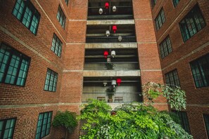 A multi-story brick building with multiple balconies, each with a red and white fire extinguisher.