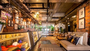 A cozy interior with a brick wall, a sofa with cushions, a display case with hats, and framed pictures on the wall. - Rosa Malacca (Malacca City)